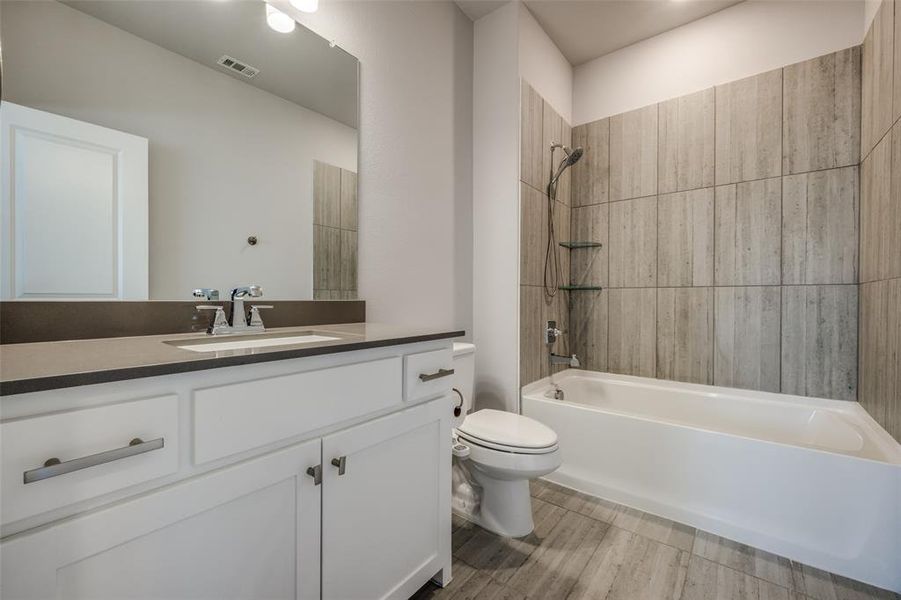 Full bathroom featuring visible vents, toilet, wood finished floors, bathing tub / shower combination, and vanity