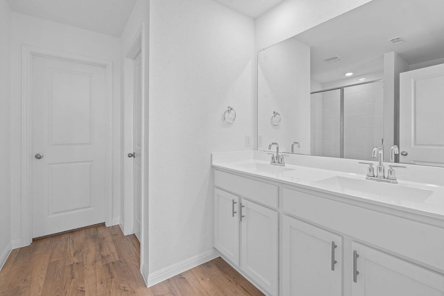 Bathroom with double vanity, light wood-type flooring, and a shower stall