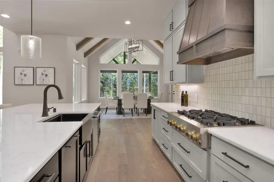 Vaulted ceilings with exposed beams frame the elegant dining area, perfectly positioned just beyond the gourmet kitchen for effortless entertaining.