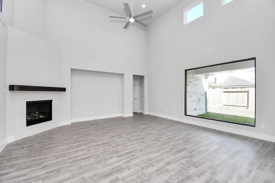 Family room flooded with natural light through the expansive windows.  The premium tile flooring adds a touch of luxury to the space, creating the perfect setting for relaxing moments and cherished gatherings with loved ones.
