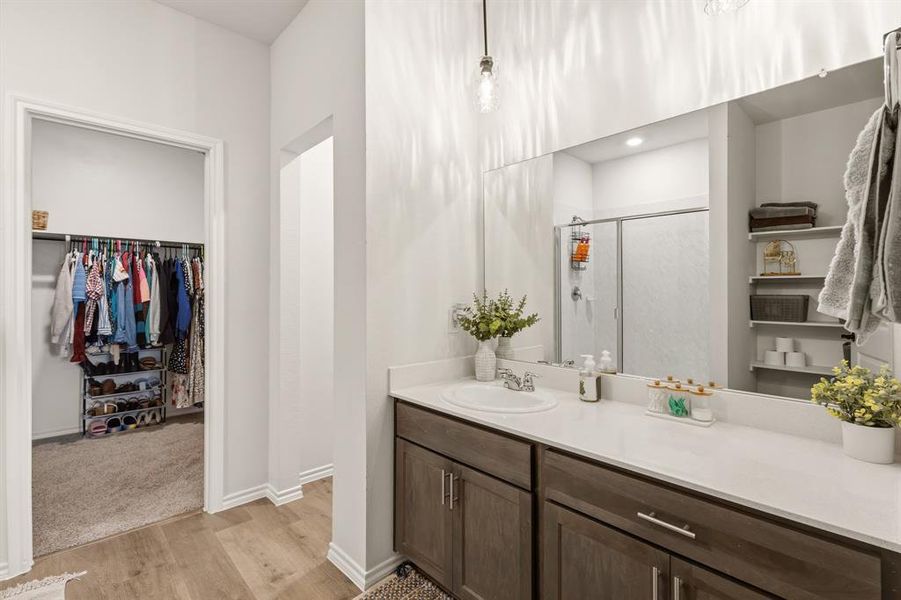 Primary bathroom features a vanity with a white countertop and dark wood cabinetry, a large mirror, and a shower with a sliding glass door Primary bathroom features a vanity with a white countertop and dark wood cabinetry, a large mirror, and a shower with a sliding glass door