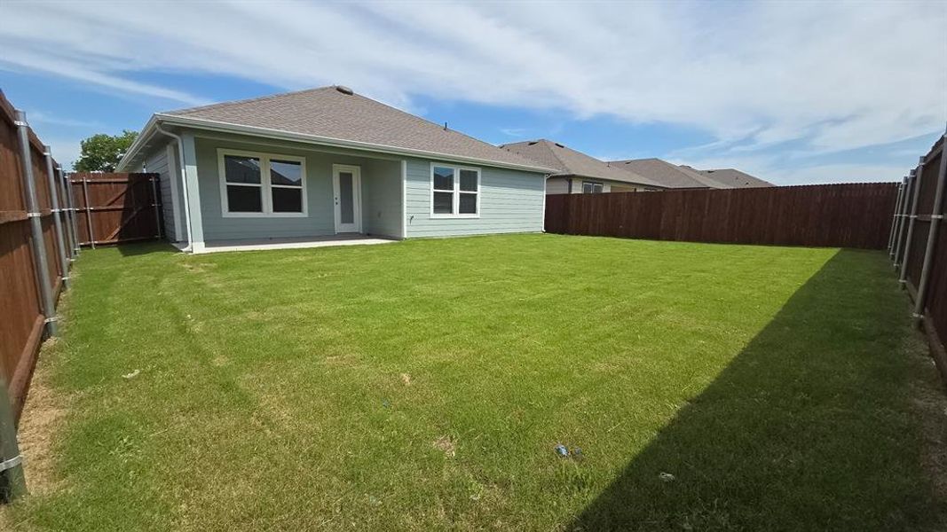 Expansive backyard featuring a manicured lawn, a concrete patio, and full perimeter fencing Expansive backyard featuring a manicured lawn, a concrete patio, and full perimeter fencing