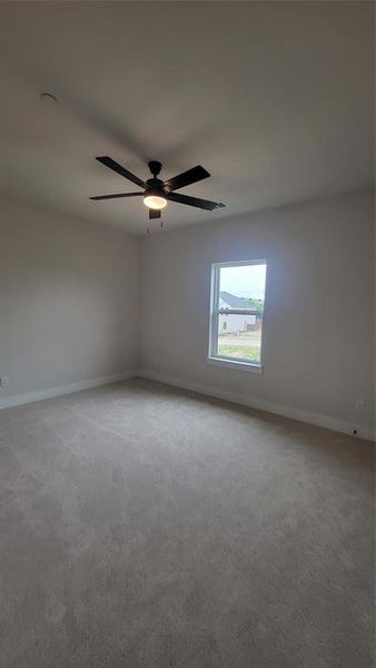 Carpeted empty room featuring baseboards and ceiling fan