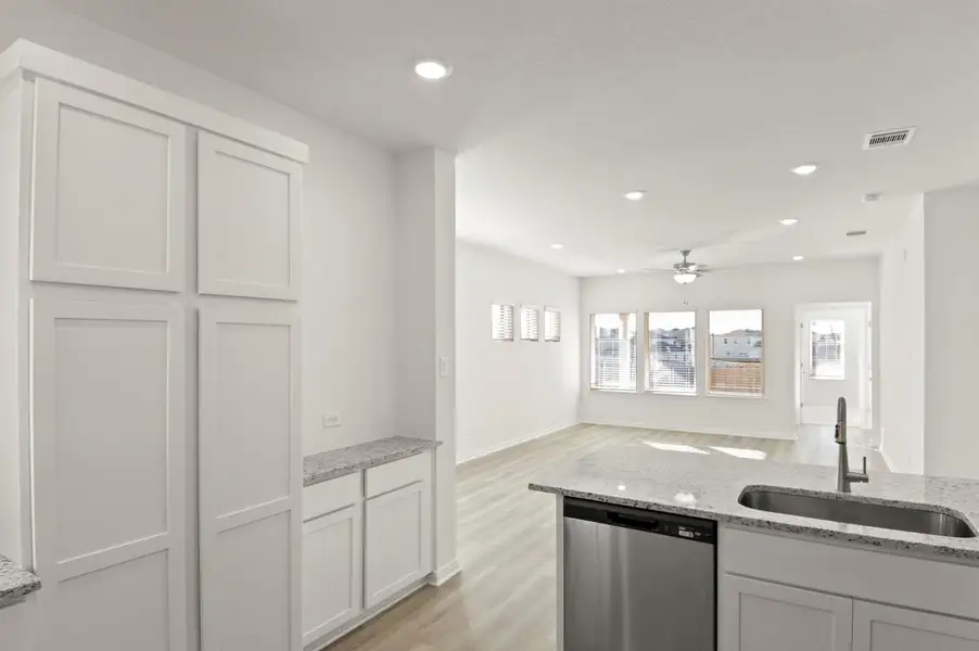 Kitchen featuring light stone counters, dishwasher, white cabinets, recessed lighting, and light wood finished floors