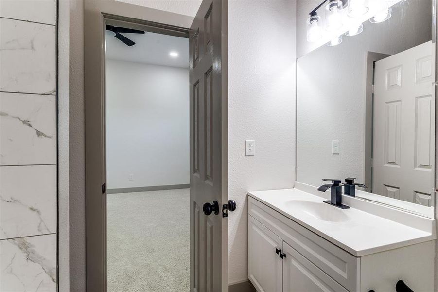 Bathroom with a textured wall, vanity, ceiling fan, and carpet floors Bathroom with a textured wall, vanity, ceiling fan, and carpet floors
