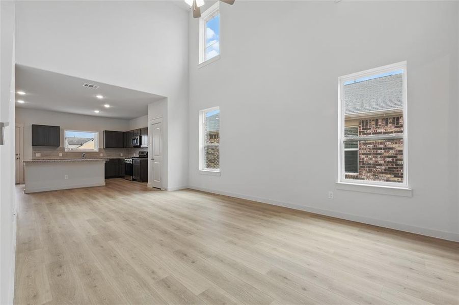 Unfurnished living room with light wood finished floors and a high ceiling