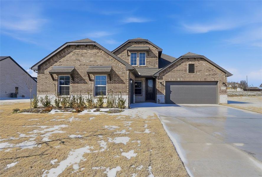 View of front of property with brick siding, driveway, and a garage