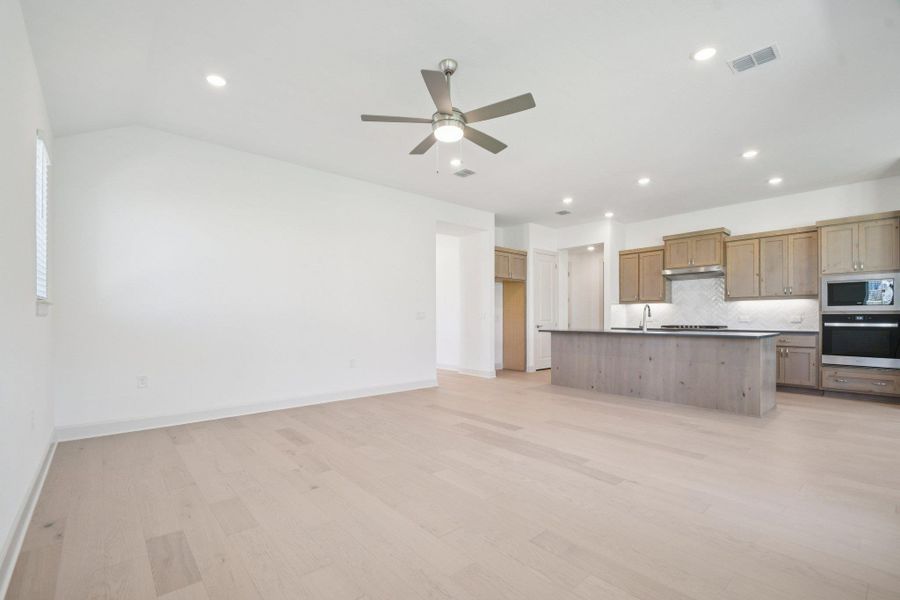 Kitchen featuring open floor plan, stainless steel oven, light wood finished floors, decorative backsplash, and recessed lighting Kitchen featuring open floor plan, stainless steel oven, light wood finished floors, decorative backsplash, and recessed lighting