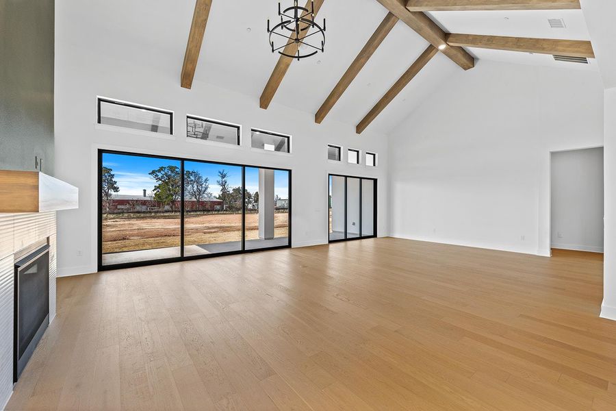 Unfurnished living room featuring a glass covered fireplace, light wood finished floors, and suspended lighting