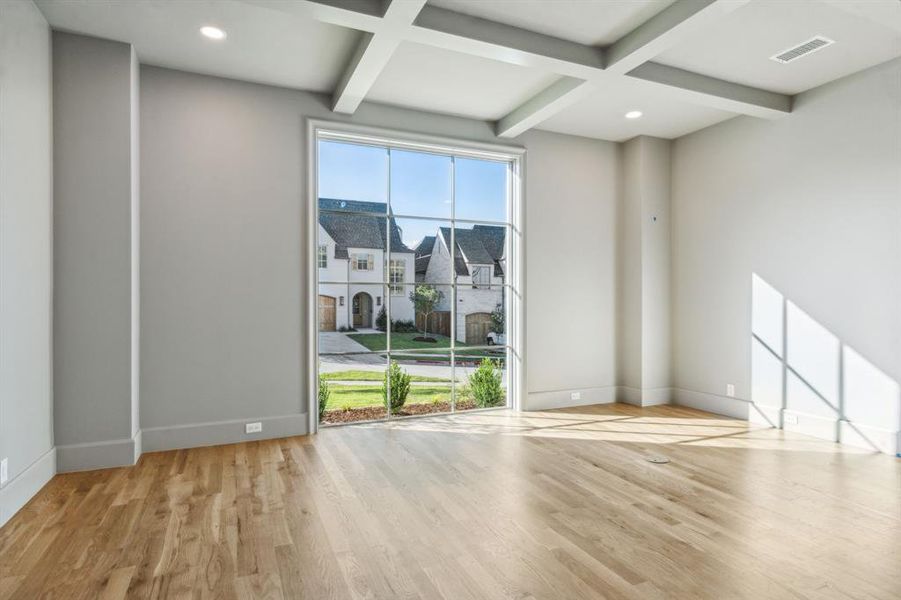 Study featuring light hardwood floors, beamed ceiling, and coffered ceiling