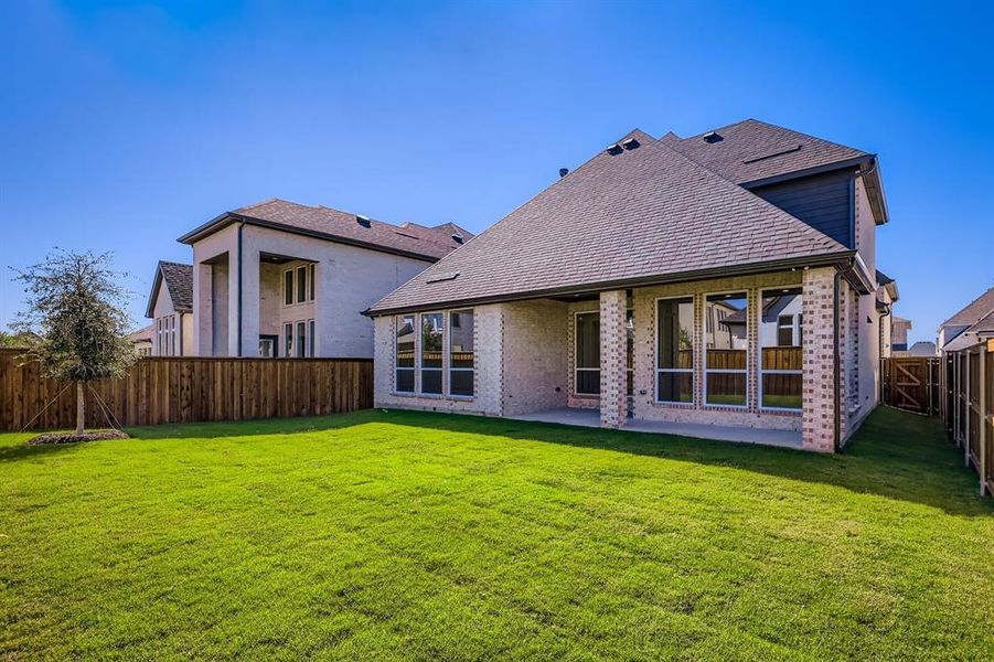 Rear view of house featuring a fenced backyard, a patio, roof with shingles, and brick siding