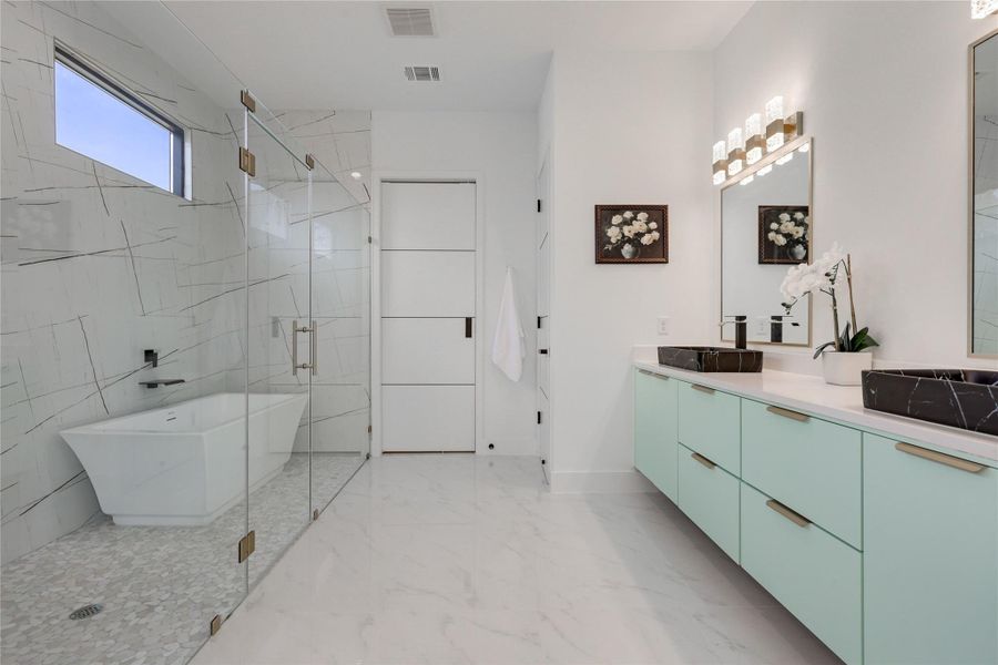 Full bath featuring a marble finish shower, double vanity, a freestanding tub, and light marble finish flooring