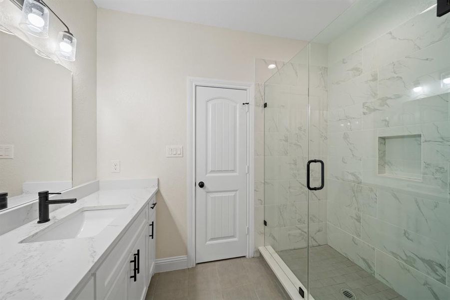 Bathroom with a shower with door, vanity, and tile patterned flooring