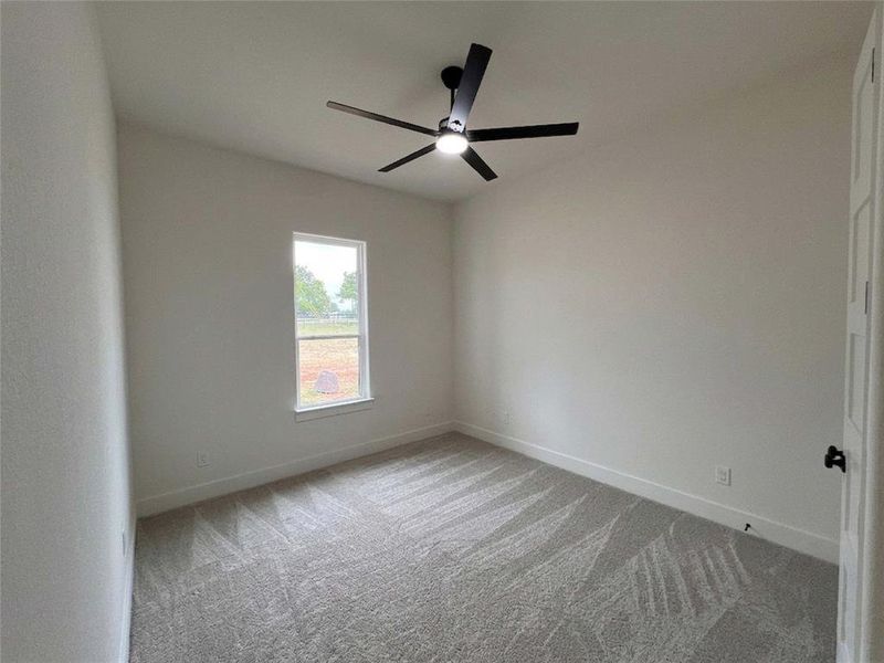 Spacious room featuring vaulted ceilings, a contemporary ceiling fan with integrated lighting, a single window providing natural illumination, and plush patterned carpeting