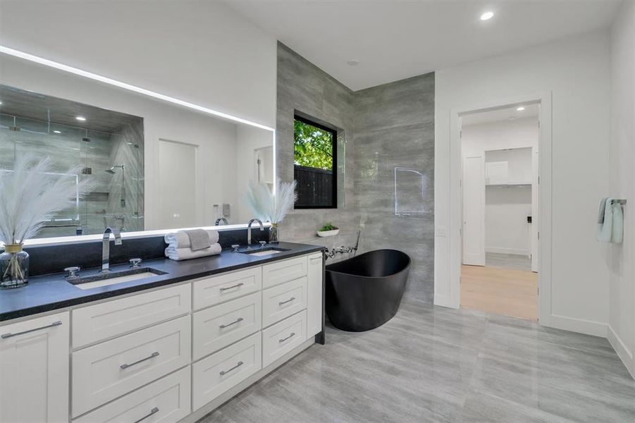 Bathroom with wood-type flooring, separate shower and tub, vanity, and tile walls