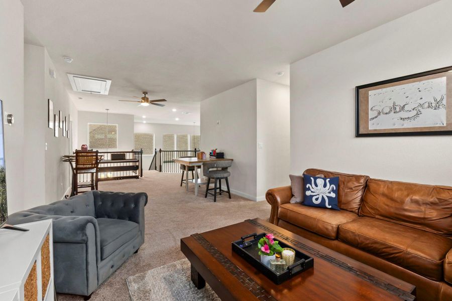Carpeted upper-level living area with recessed lighting, a ceiling fan, white baluster railings, and multiple windows