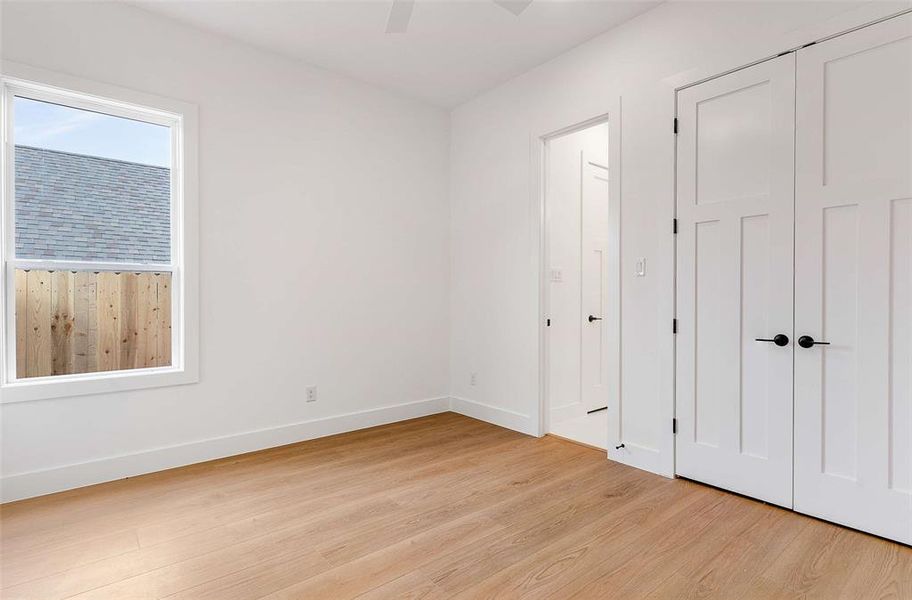 Unfurnished bedroom with light wood-type flooring, a closet, and a ceiling fan