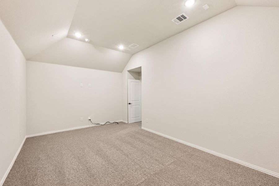 Empty bedroom with vaulted ceiling, recessed lighting, and neutral carpet flooring