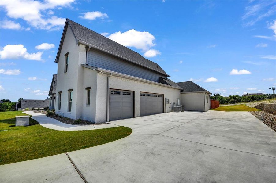 View of home's exterior featuring a garage, central AC unit, and a yard