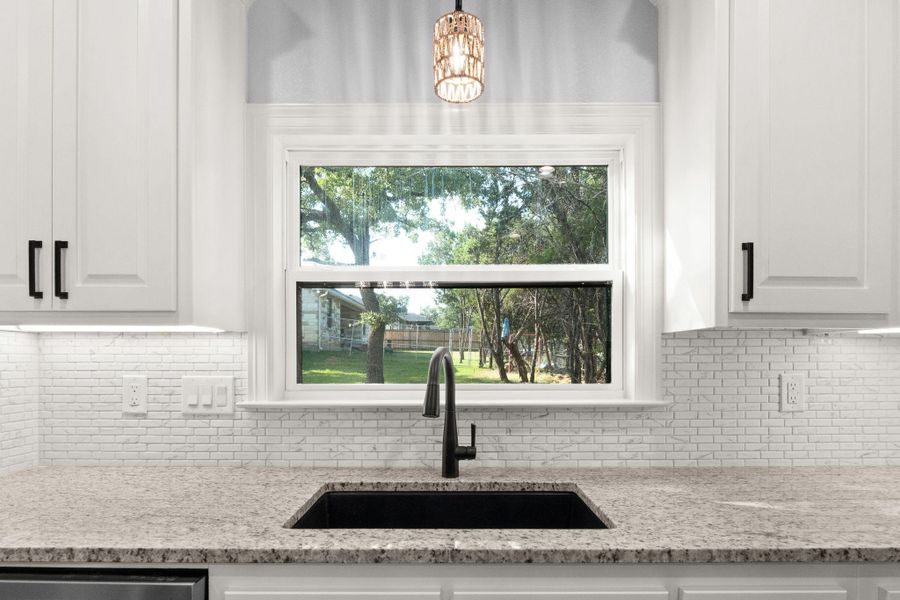 Kitchen featuring tasteful backsplash, white cabinets, and light stone counters