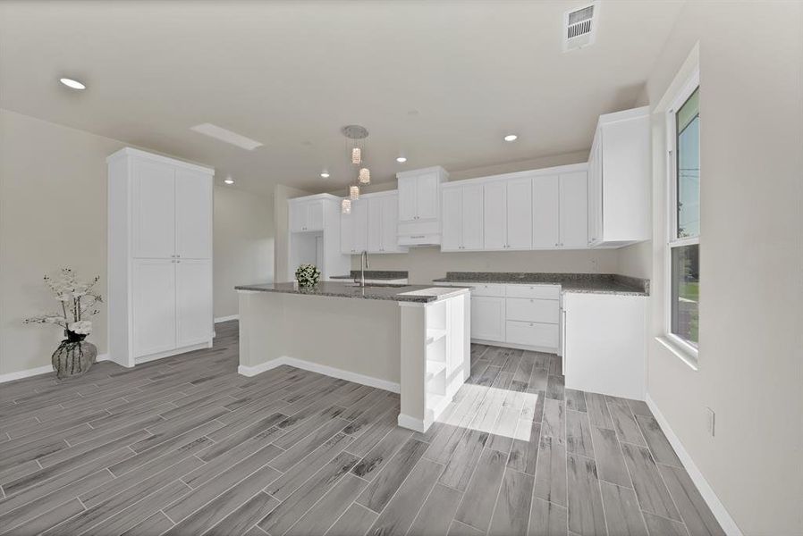 Kitchen featuring light wood-style floors, recessed lighting, a center island with sink, white cabinetry, and premium range hood