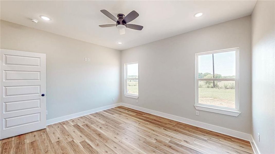 Unfurnished room with plenty of natural light, light wood-type flooring, a ceiling fan, and recessed lighting Unfurnished room with plenty of natural light, light wood-type flooring, a ceiling fan, and recessed lighting