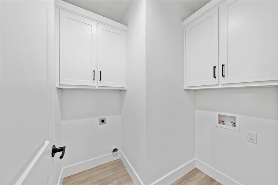 Washroom featuring cabinet space, baseboards, light wood finished floors, and hookup for an electric dryer