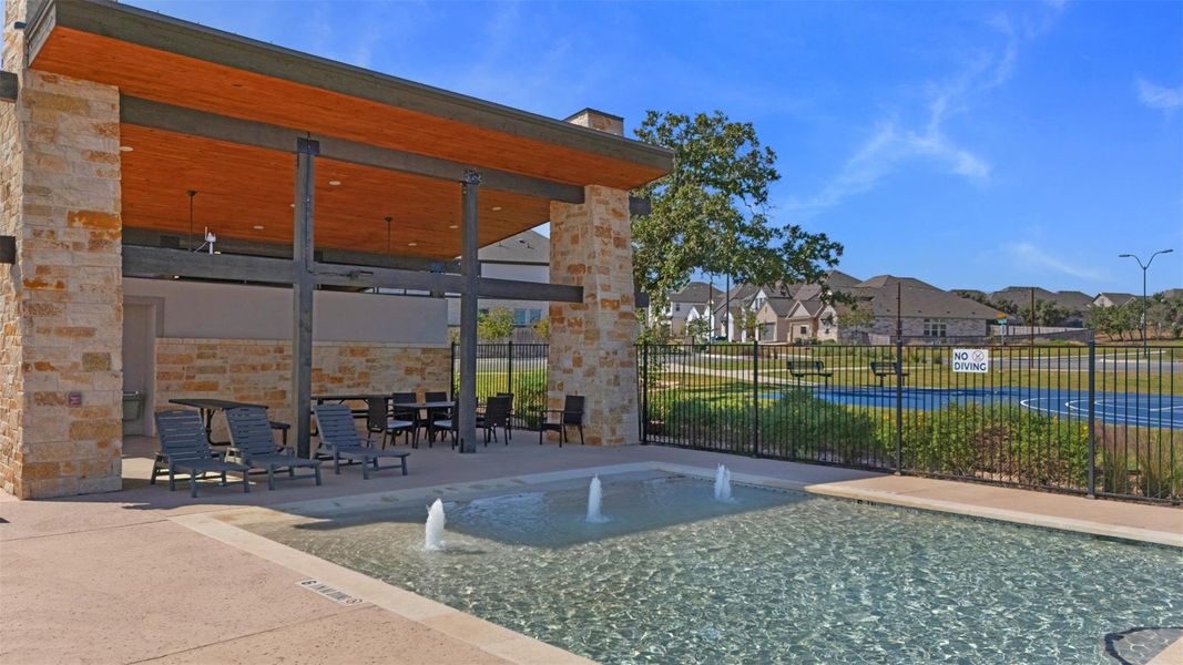 Outdoor pool with multiple water features, surrounded by a stone-clad cabana featuring a wood-panel ceiling and exposed beams Outdoor pool with multiple water features, surrounded by a stone-clad cabana featuring a wood-panel ceiling and exposed beams