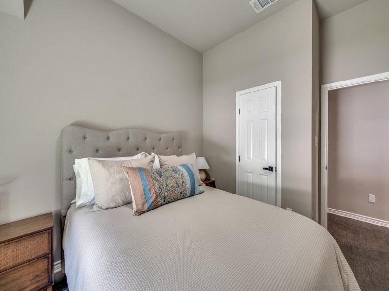 Bedroom featuring lofted ceiling, baseboards, and dark colored carpet Bedroom featuring lofted ceiling, baseboards, and dark colored carpet