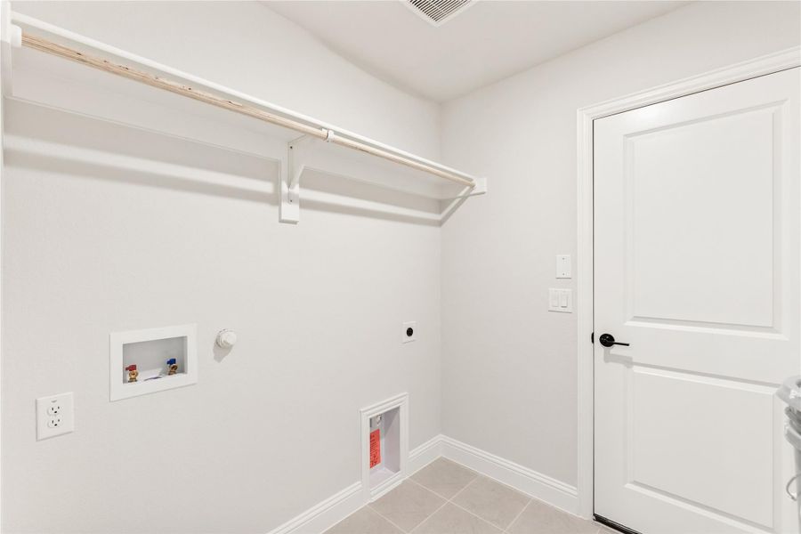 Laundry room with wall-mounted shelf, washer and dryer hookups, and tile floor Laundry room with wall-mounted shelf, washer and dryer hookups, and tile floor