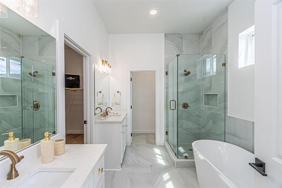 Bathroom featuring healthy amount of natural light, a spacious closet, two vanities, a marble finish shower, and recessed lighting