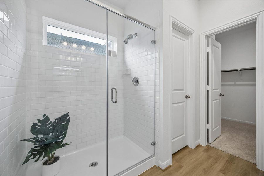 Full bath with a stall shower, a spacious closet, and light wood finished floors