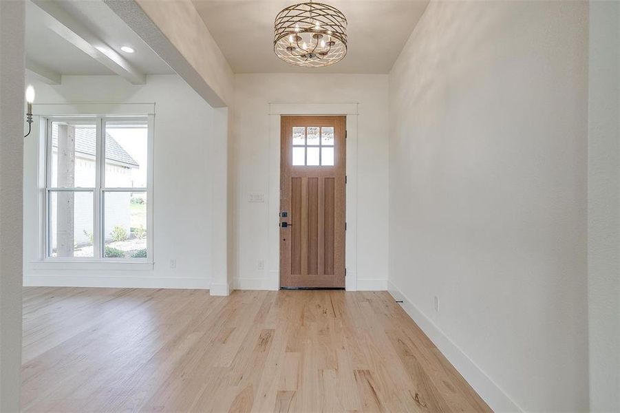 Entryway with light wood-type flooring, baseboards, and a chandelier