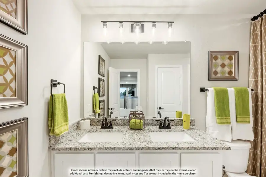 Bathroom with double sink vanity, granite countertop, white cabinets, and large mirror with overhead lighting