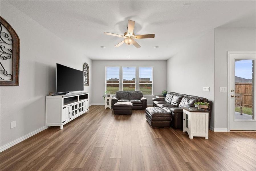 Living room with a wealth of natural light, ceiling fan, and luxury vinyl flooring.