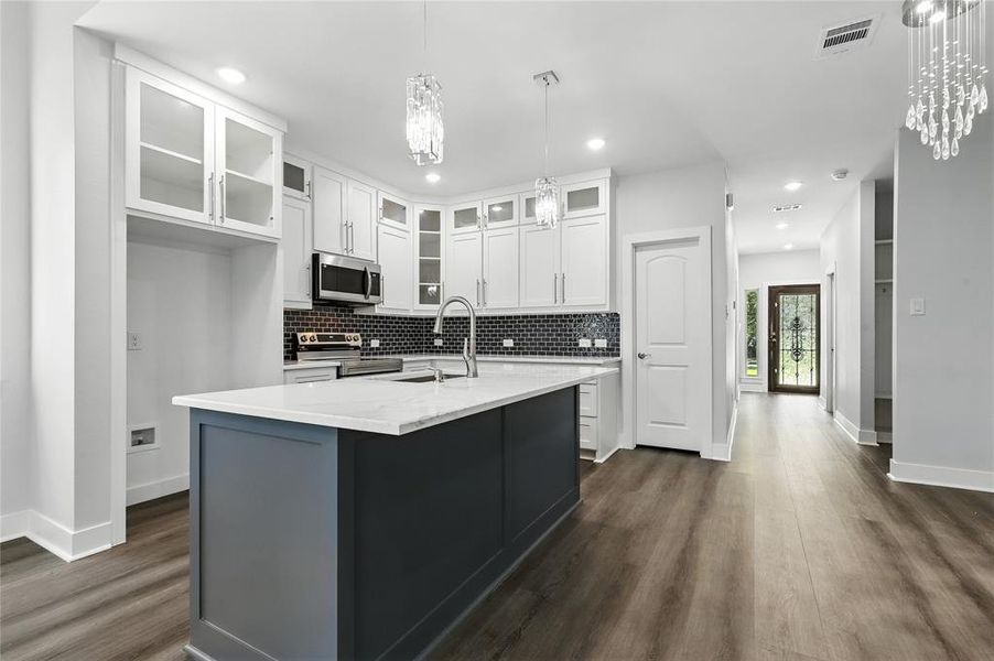 Kitchen with white cabinets, backsplash, stainless steel appliances, and recessed lighting