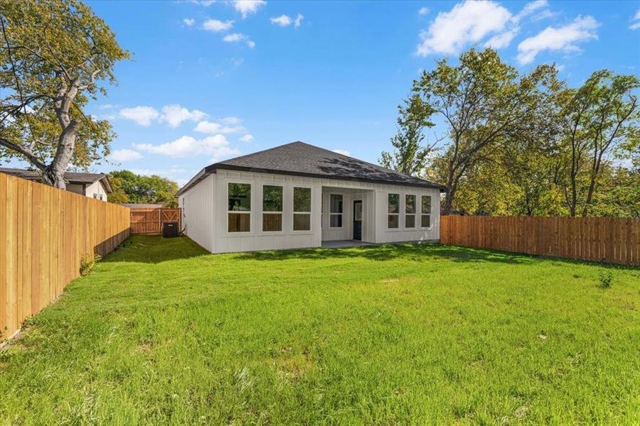 Rear view of property with a patio, a fenced backyard, and a shingled roof