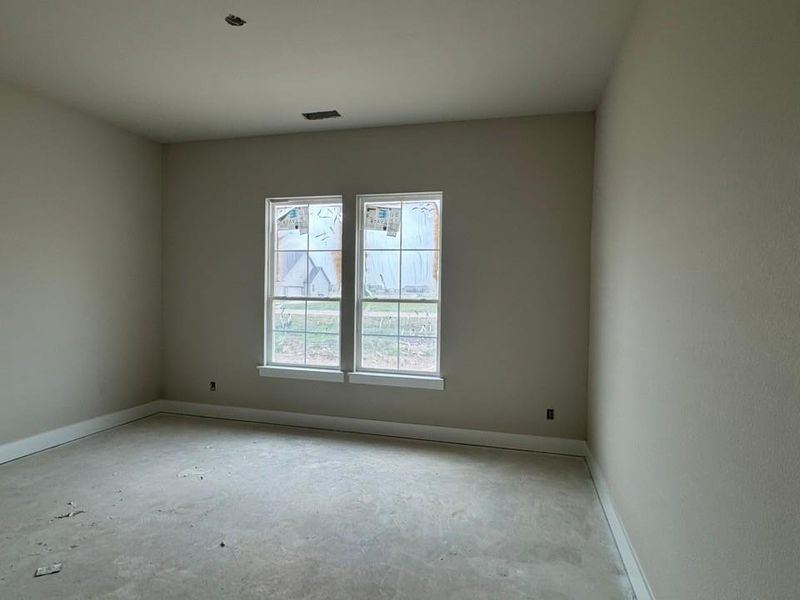 Bright interior space featuring two large windows with mullions, light-toned walls, and white baseboards