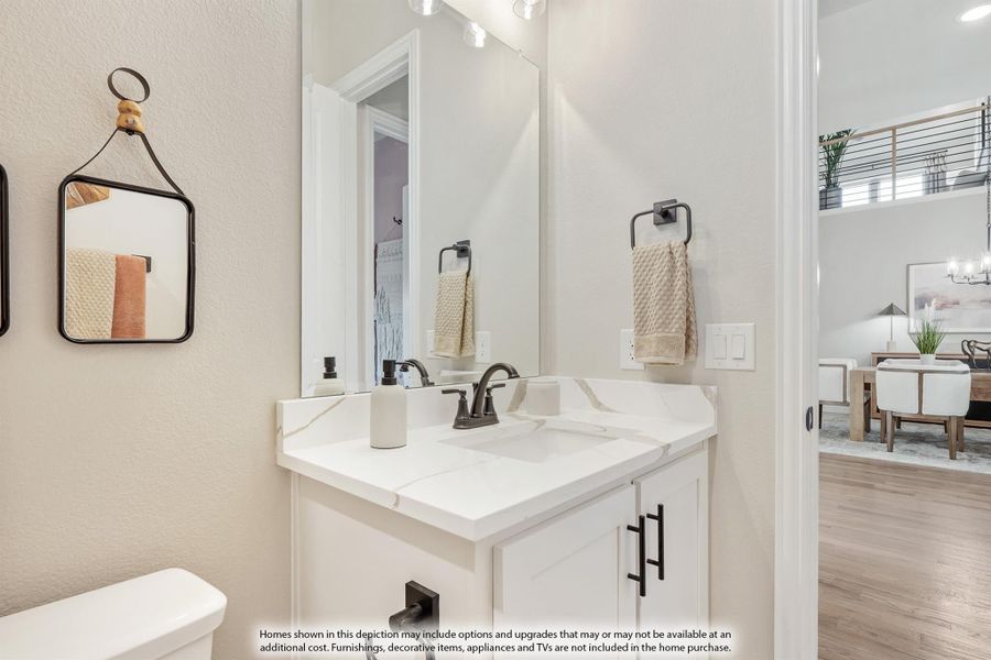 Powder room with white vanity, quartz countertop, dark hardware, and large mirror above single sink Powder room with white vanity, quartz countertop, dark hardware, and large mirror above single sink