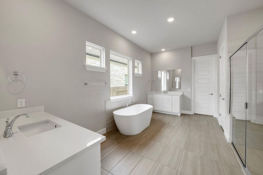 Full bathroom with two vanities, a stall shower, a soaking tub, and recessed lighting Full bathroom with two vanities, a stall shower, a soaking tub, and recessed lighting