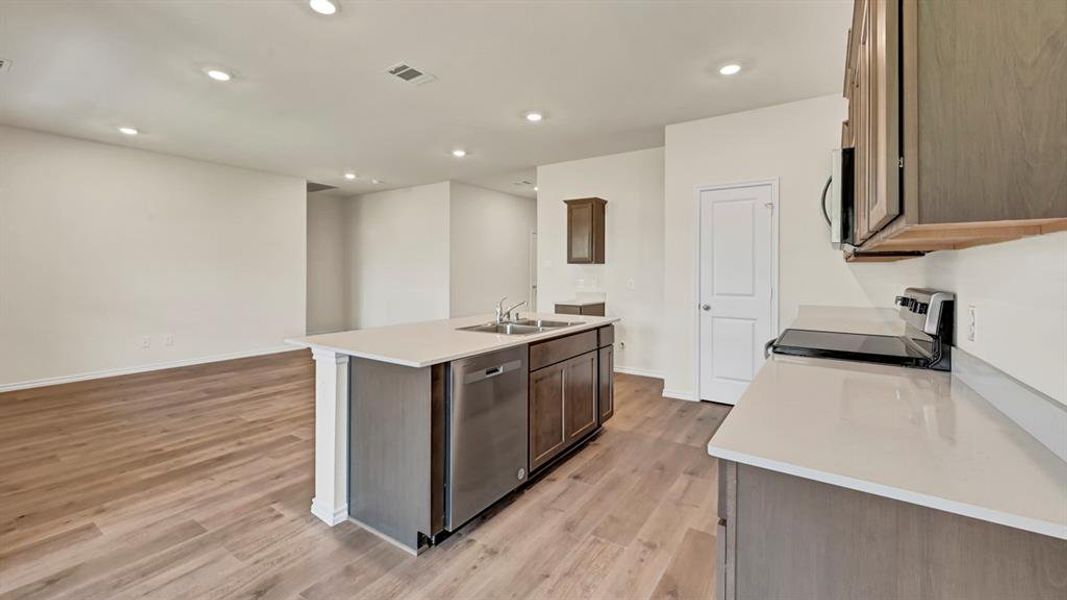 Kitchen island with a double basin sink, stainless steel dishwasher, and light-toned countertop