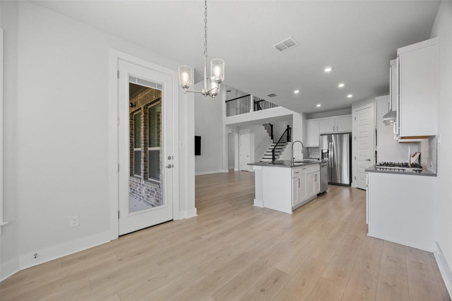 An open-concept living space presents light wood flooring and a kitchen island with seating.