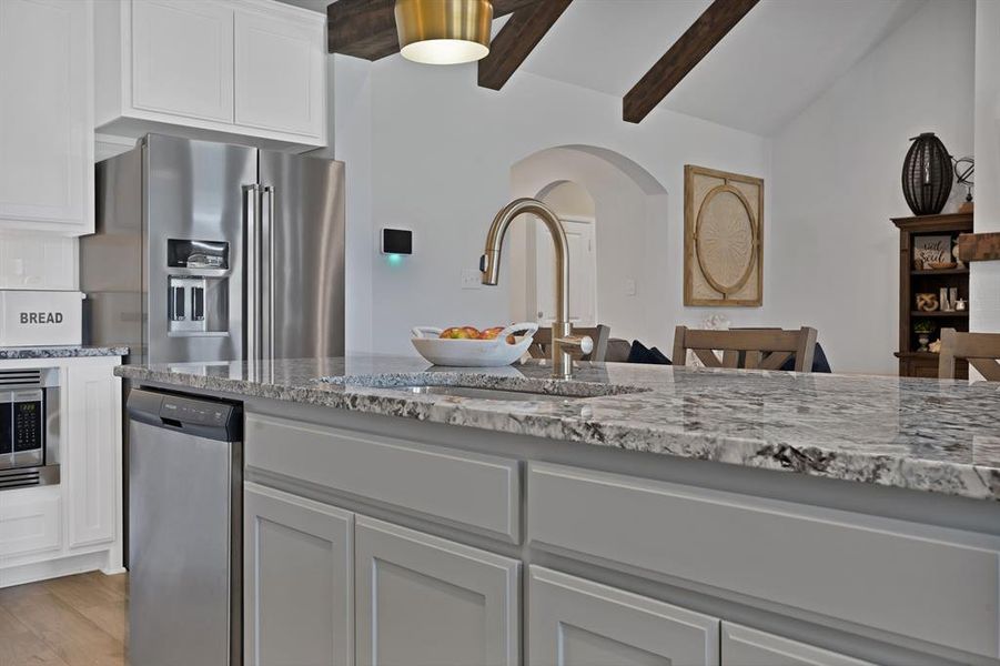 Kitchen with stainless steel appliances, light stone countertops, arched walkways, white cabinetry, and light wood-style floors Kitchen with stainless steel appliances, light stone countertops, arched walkways, white cabinetry, and light wood-style floors