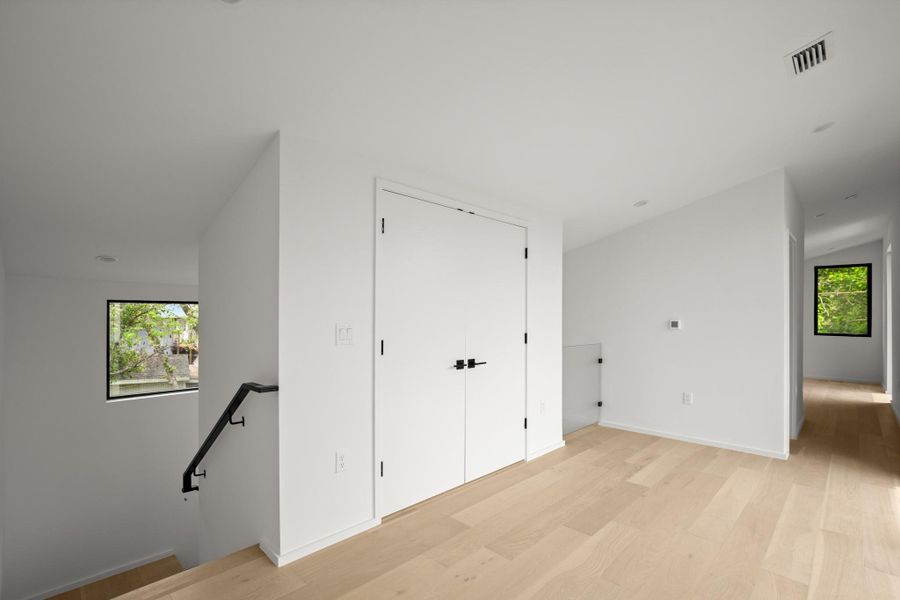 Corridor with an upstairs landing and light wood finished floors