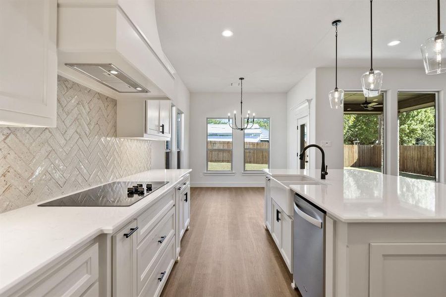 Kitchen with white cabinets, pendant lighting, tasteful backsplash, a chandelier, and light stone countertops