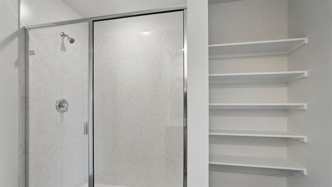 Shower enclosure with chrome fixtures and integrated shelving