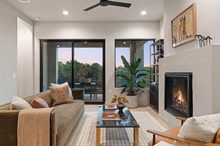 A cozy living space offers a warm fireplace, recessed lighting, and a serene balcony view. A cozy living space offers a warm fireplace, recessed lighting, and a serene balcony view.