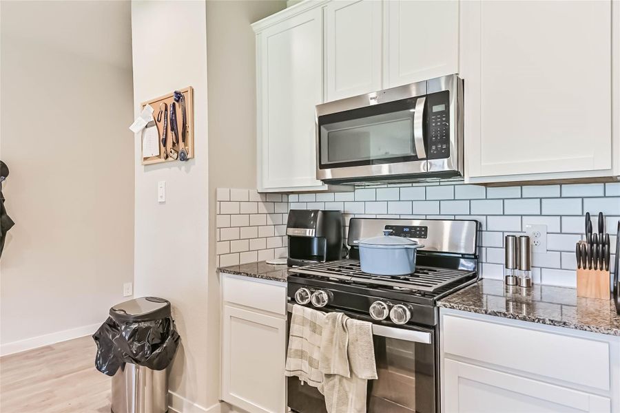 Modern island kitchen with gas stove, subway tile backsplash, stainless steel appliances, and gorgeous countertops—perfect for cooking and entertaining.
