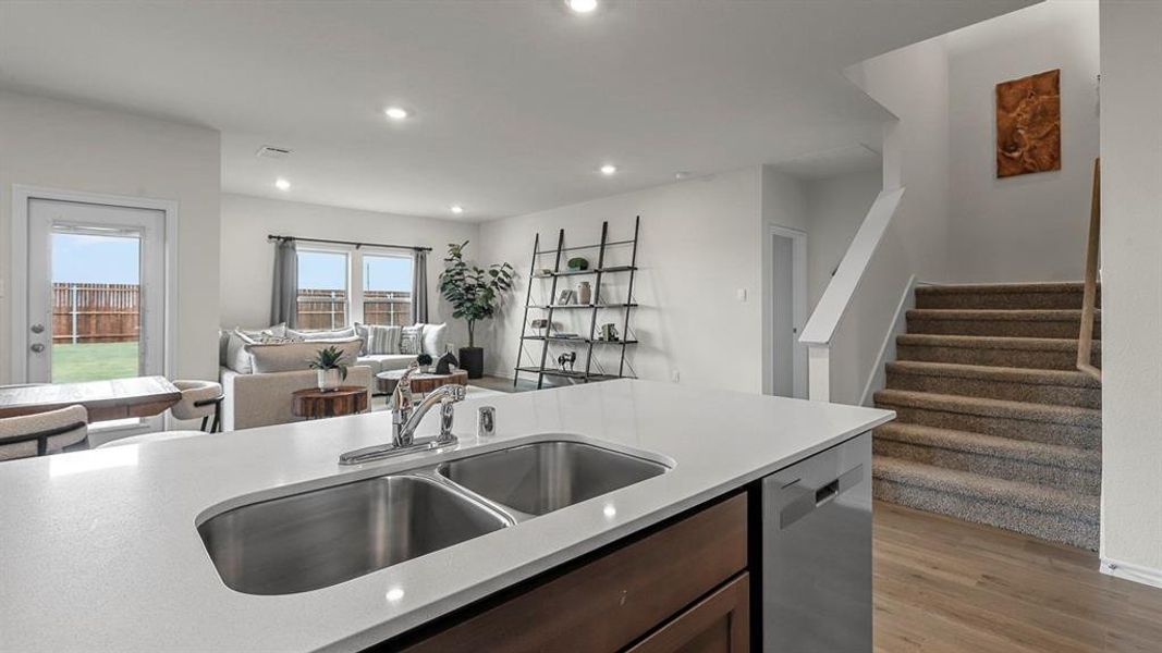 Kitchen featuring dark wood finish cabinets, open floor plan, stainless steel dishwasher, light wood finished floors, and recessed lighting