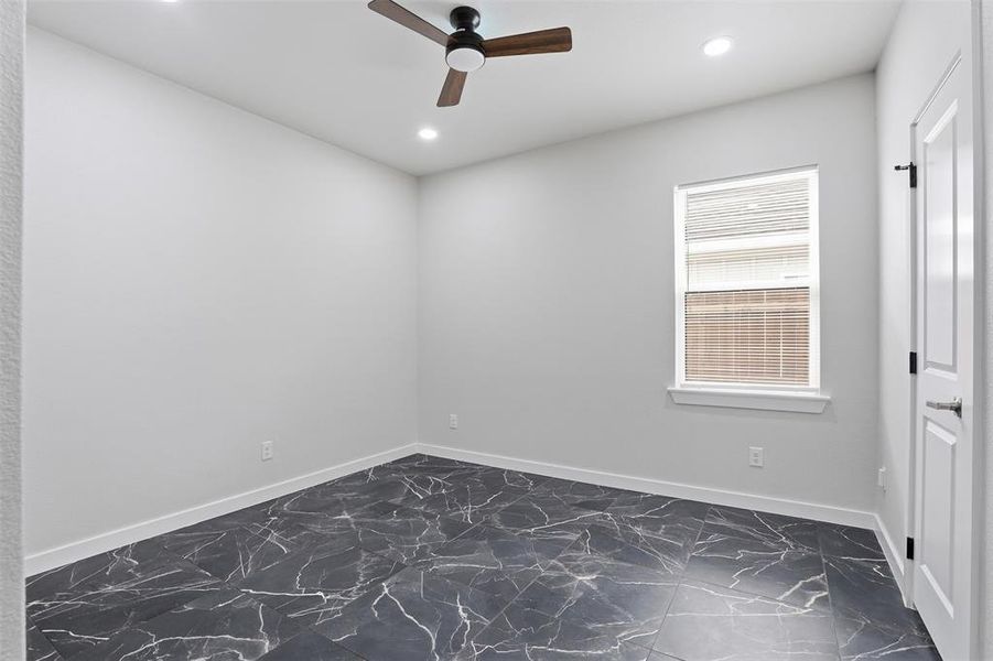Spacious room featuring dark large format tile flooring with white veining, recessed lighting, a modern ceiling fan, a window with blinds, and white trim throughout